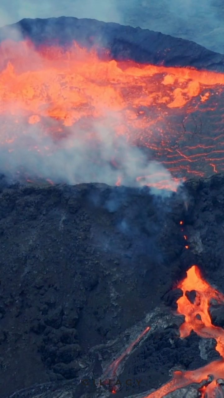 Aerial frame of a fissure eruption, lava breaking through dark rock